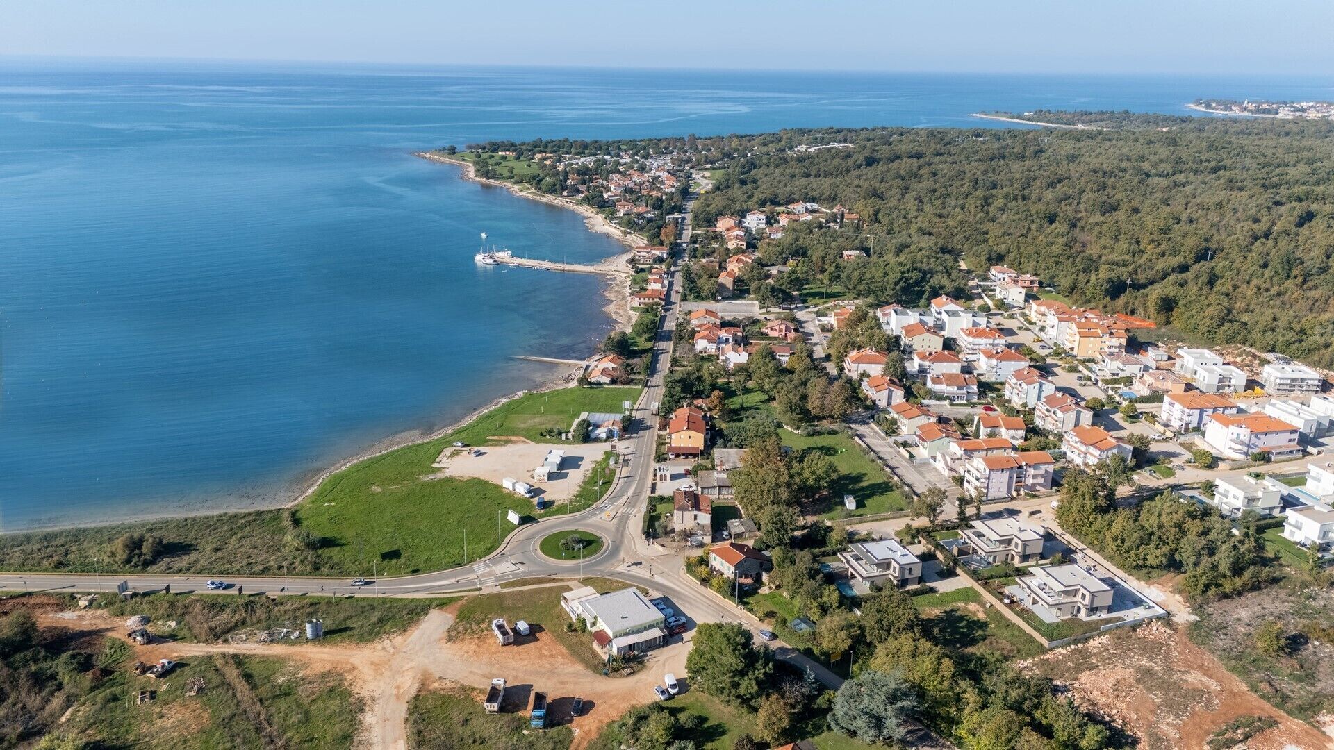 Eine Luftaufnahme einer Küstenwohngegend mit Häusern, einer Straße und einem Strand.