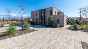 A modern two-story house with a paved driveway and landscaped garden. - Ground-Floor Apartment with Private Pool and Terrace in Istria, 150 Meters from the Sea (Brtonigla)