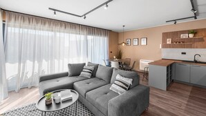 A modern living room with a grey sectional sofa, a round coffee table, and a dining area with a small table and chairs. - Ground-Floor Apartment with Private Pool and Terrace in Istria, 150 Meters from the Sea (Brtonigla)