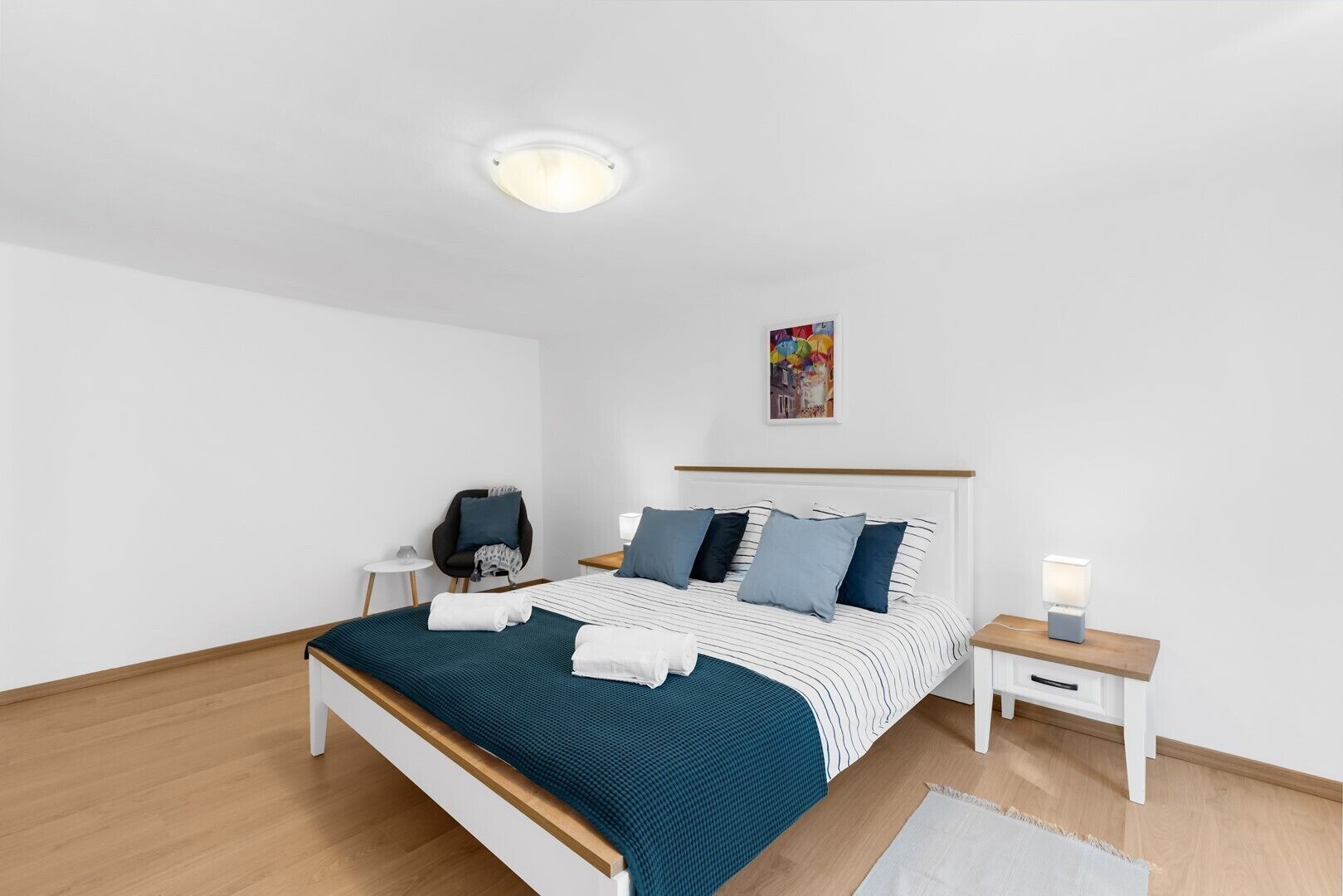 Ein modernes Hotelzimmer mit einem Einzelbett, einem Sessel, einem kleinen Tisch und einem Nachttisch.