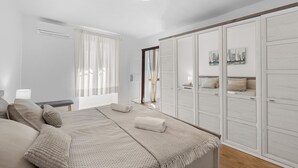 Een slaapkamer met een bed, nachtkastjes, een garderobe en een raam met gordijnen.