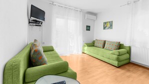 A modern living room with green sofas, a flat-screen TV, and a radiator.