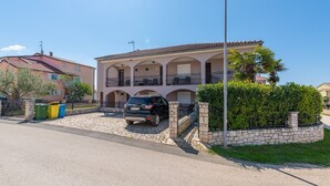 A two-story building with a stone facade, a car parked in front, and a clear sky.