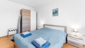 A neatly made bed with blue and white linens, a wooden headboard, and a bedside table with a lamp.