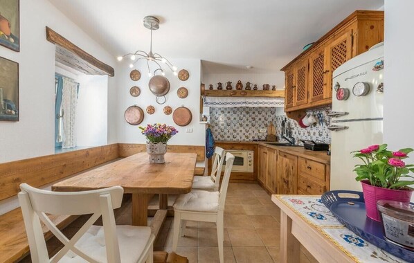 A kitchen with wooden cabinets, a white refrigerator, and a dining table with chairs. - Charming City-Center Cottage Just 20 Meters from the Beach in Novigrad (Novigrad)