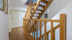 A wooden staircase with a handrail, white walls, and a door at the bottom.