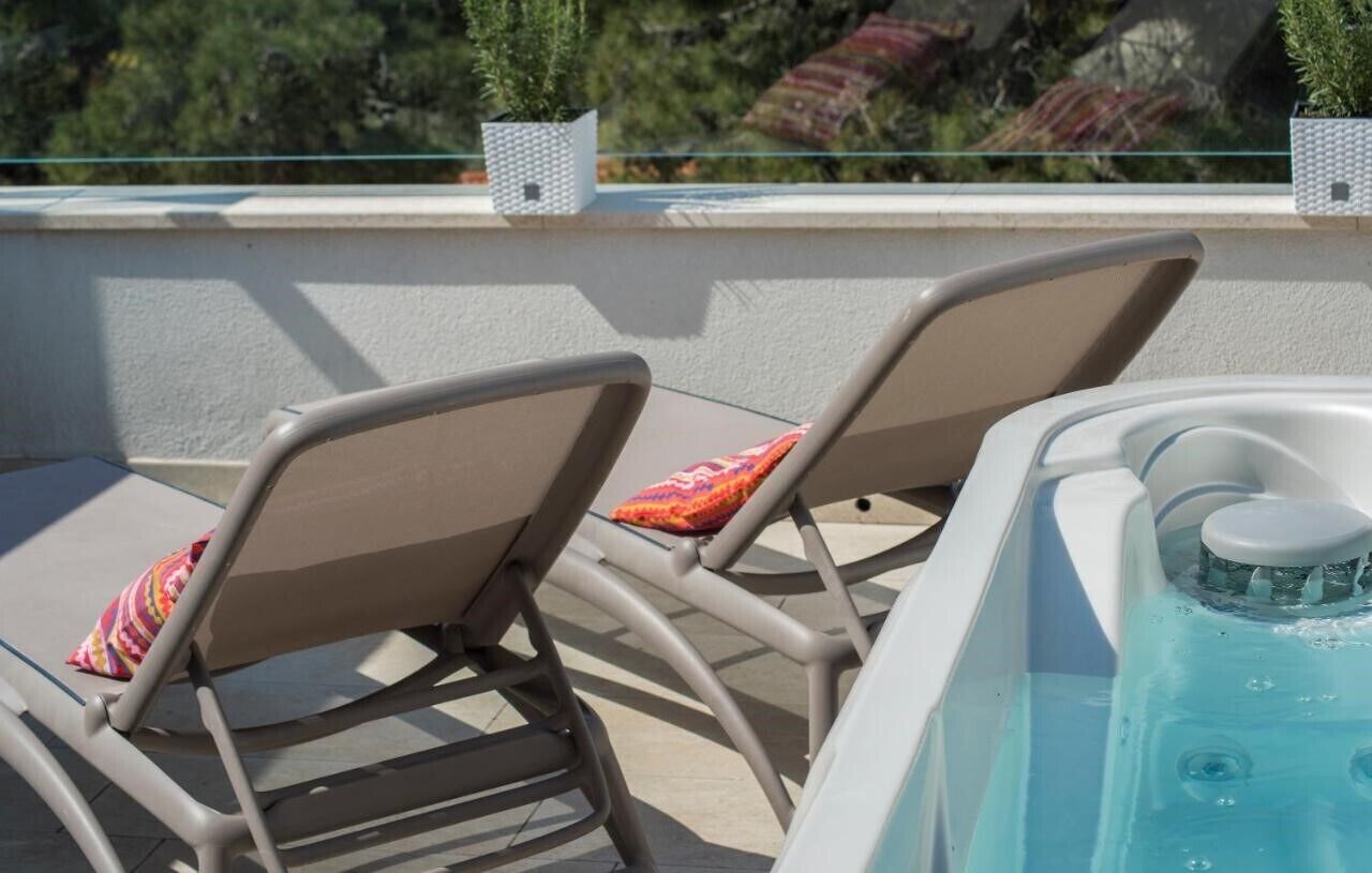 A poolside area with two lounge chairs and a hot tub.