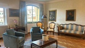A living room with a sofa, two armchairs, a coffee table, and a lamp. There are two paintings on the wall and a window with curtains. - PONTE VECCHIO VIEW FLORENCE (Firenze)