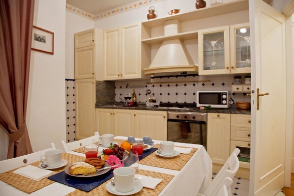 A breakfast setup with a table, chairs, and a kitchen area with cabinets, a microwave, and a stove.