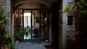 A stone building entrance with a metal gate, potted plants, and a number plaque. - PONTE VECCHIO VIEW FLORENCE (Firenze)