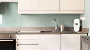 Eine moderne Küche mit weißen Schränken, einer Edelstahl-Spüle und einem eingebauten Backofen.
