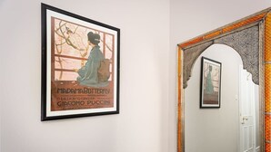 Ein gerahmtes Poster von 'Madama Butterfly' an einer Wand, eine Tür mit aufwendiger Gestaltung und ein gerahmtes Bild darüber.
