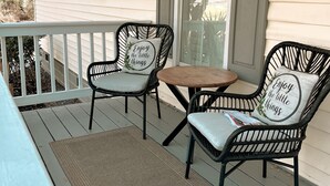 A porch with two wicker chairs and a small table, a doormat, and a window with shutters. - Beautifully renovated,  walkable home in Charleston - close to everything! (Charleston)
