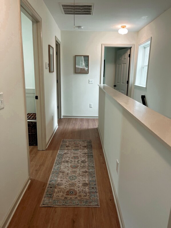 A narrow hallway with wooden flooring and a patterned rug.
