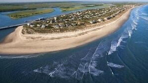 An aerial view of a coastal area with a sandy beach, a small settlement with houses, and a river or bay to the left. - Beautifully renovated,  walkable home in Charleston - close to everything! (Charleston)