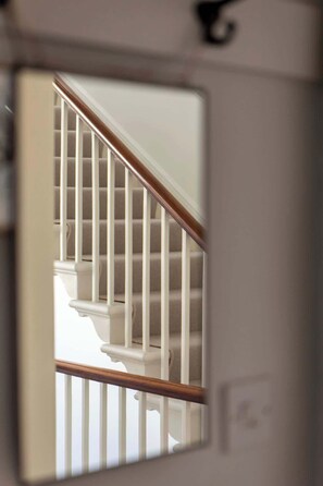 Vista a través de una ventana de una escalera con barandas blancas y una barandilla de madera.