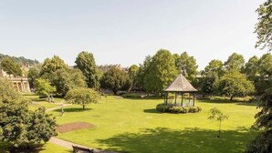 A park with a gazebo, a circular flower bed, and a stone balustrade.