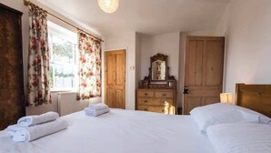 A hotel room with two beds, wooden furniture, a dresser, and a mirror.