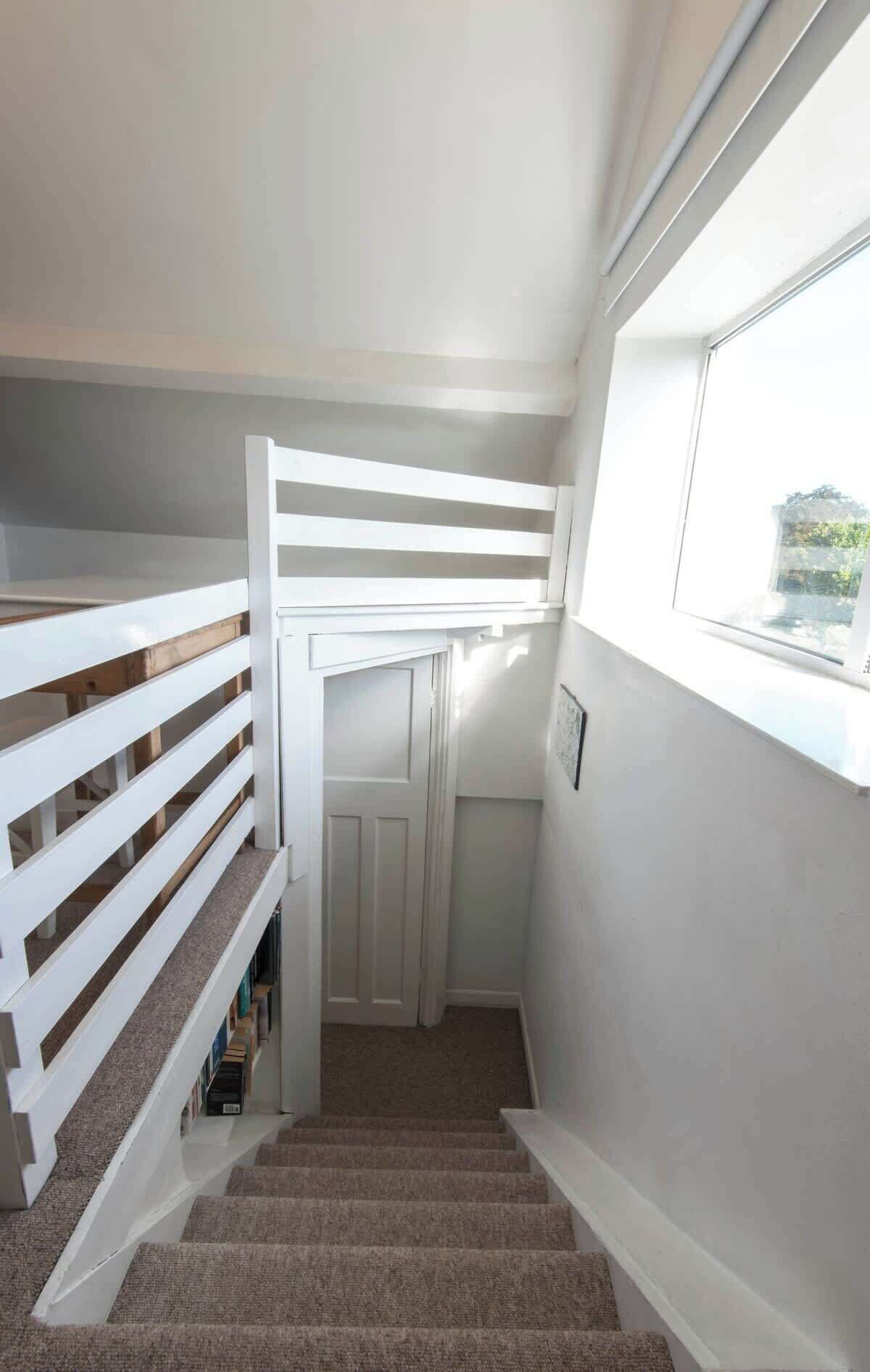 A staircase with white railings and carpeted steps leading to a door.