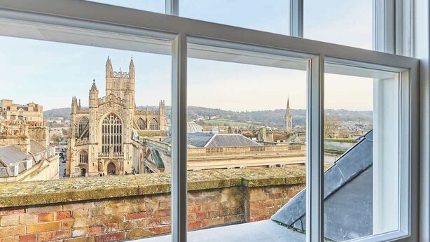 A view from a window overlooking a historic cathedral with a prominent spire, a bridge, and surrounding buildings.