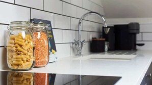 A kitchen counter with two glass jars containing pasta and lentils, a coffee maker, and a modern faucet.