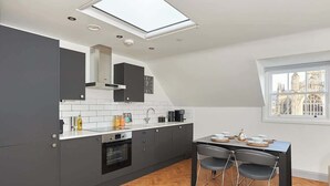 A modern kitchen with grey cabinets, a white countertop, and a dining area with a table and chairs.