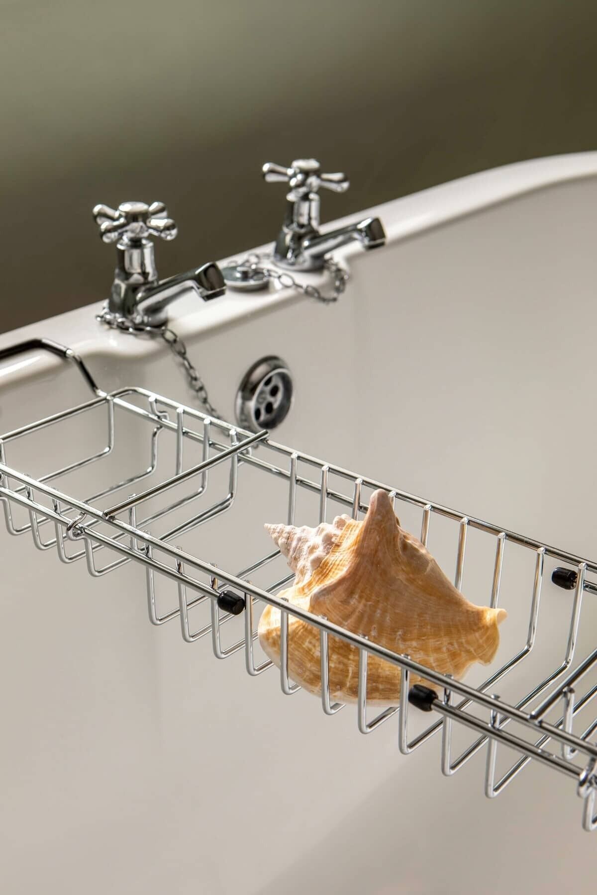 A metal rack with a seashell hanging from it, attached to a sink with a faucet.