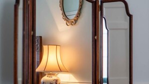 A wooden dressing table with a mirror, a lamp, and a small decorative item. - Luxury Apartment Next to Bath Abbey & Shops (Bath)