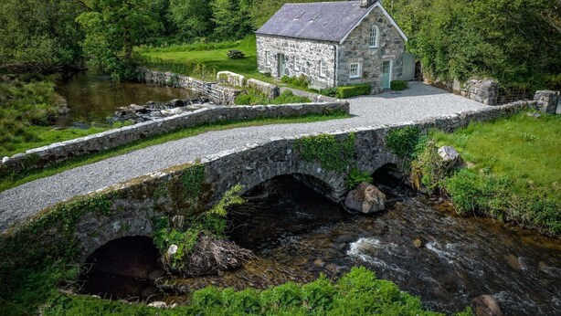 A stone bridge over a stream leading to a stone house with a garden and picnic table. - Otter Cottage - sleeps 6 guests in 3 bedrooms (Pwllheli)