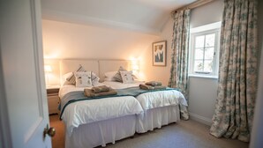 A bedroom with a large bed, two bedside tables, a window with curtains, and a framed picture on the wall. - Otter Cottage - sleeps 6 guests in 3 bedrooms (Pwllheli)