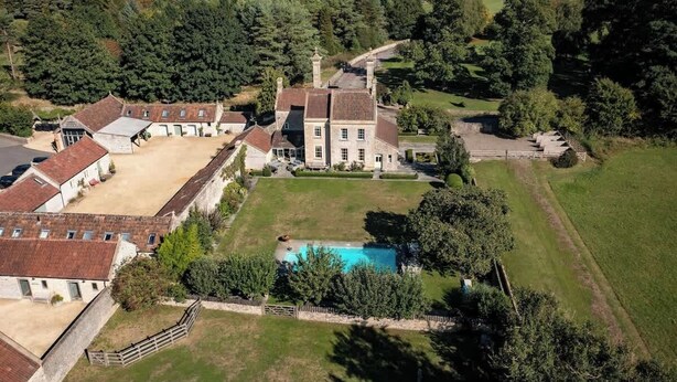 Vista aèria d'una gran propietat amb piscina, diversos edificis i extensos camps de gespa.