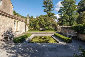 A courtyard with stone walls, a central rectangular water feature, and benches.