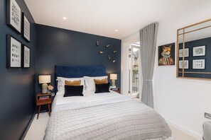 Relax in a stylish bedroom with a large bed, tufted headboard, and framed artwork.