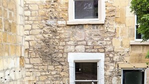 Un edificio de piedra con un pequeño patio amueblado con muebles de mimbre y una planta en maceta.