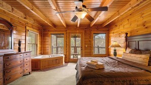 Ein Schlafzimmer in einer Blockhütte mit einem Bett, einem Schminktisch und einem großen Fenster.