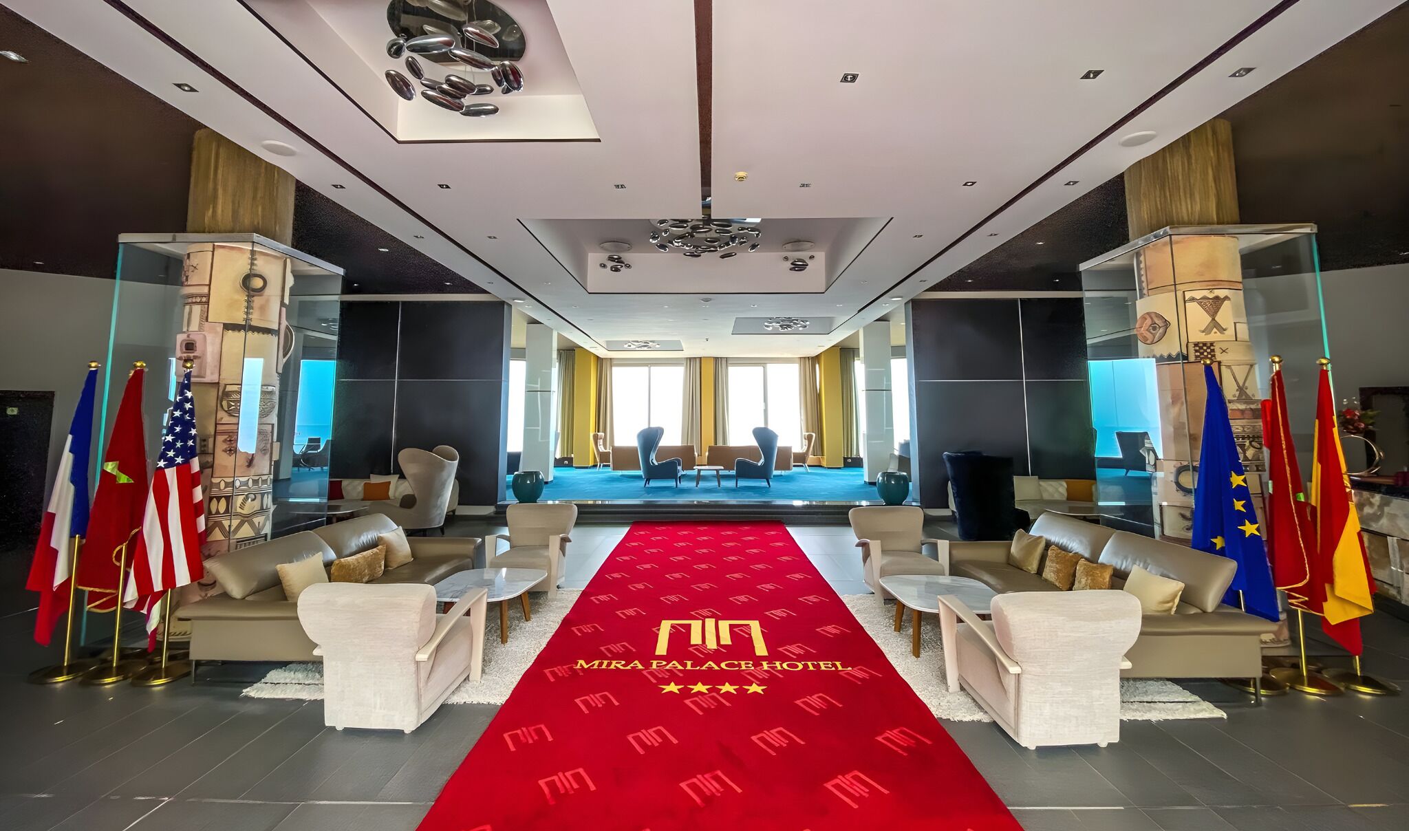 A hotel lobby with a red carpet, seating arrangements, and flags.