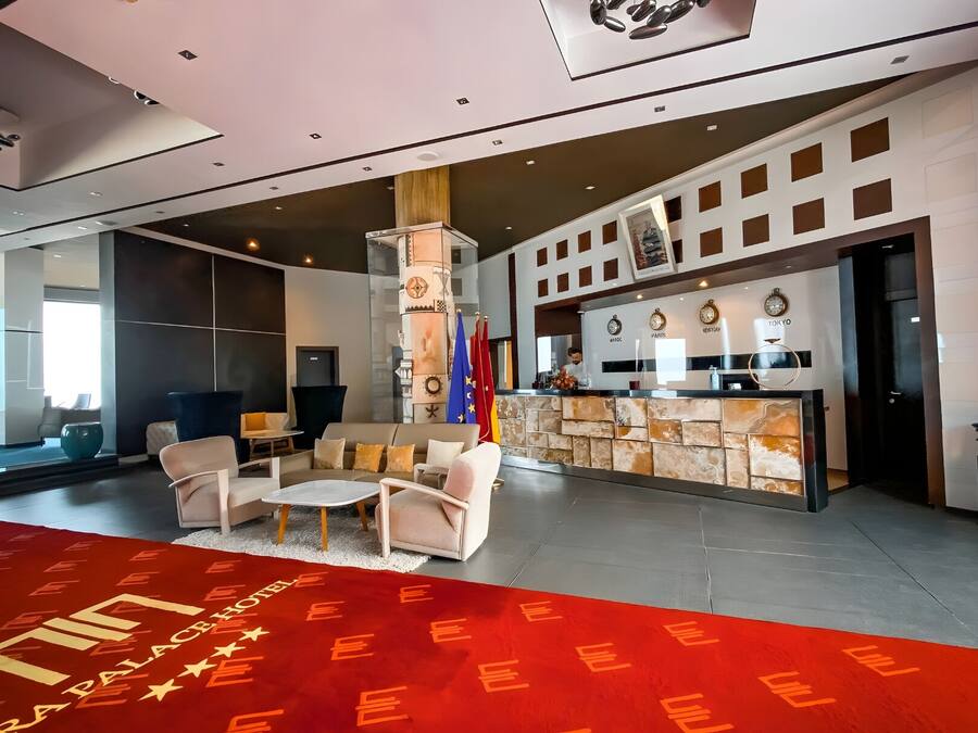 A hotel lobby with a reception desk, seating area, and a red carpet with 'PLACE HOTEL' text.
