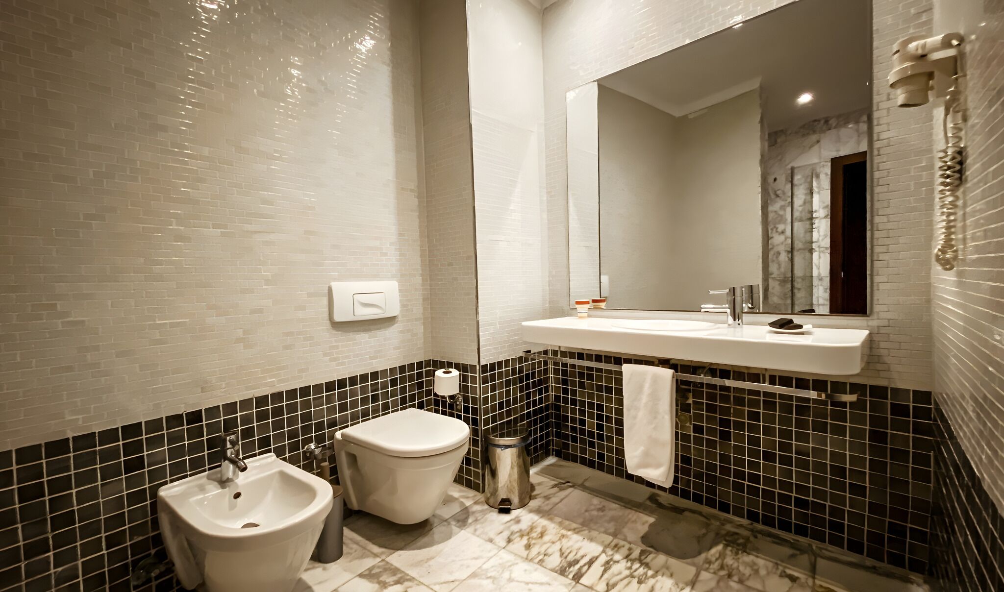 Un baño moderno con un lavamanos blanco, un espejo, un bidé y un inodoro.