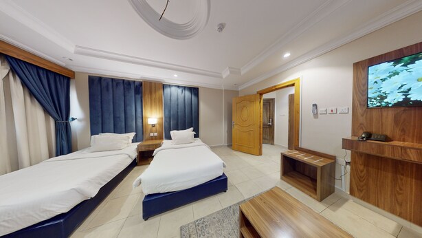 Habitación de hotel con dos camas, un televisor, un escritorio y un armario de madera.