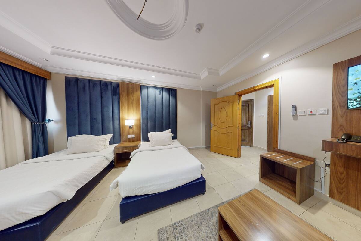 Habitación de hotel con dos camas, un televisor, un escritorio y un armario de madera.