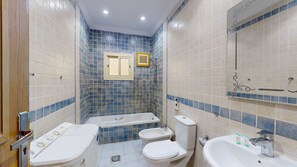 Ein Badezimmer mit Badewanne, zwei Toiletten, einem Waschbecken und einer Dusche.