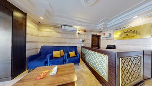 Un vestíbulo de hotel con un sofá azul, un mostrador de recepción de madera y una pared de mármol.