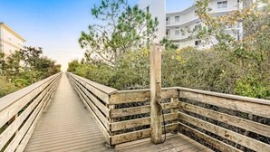 A wooden boardwalk leading to a white building with balconies, surrounded by greenery. - 🌴Walk to Beach-3BR-Lake View-Seagrove Highlands 1304🌴 (Santa Rosa Beach)