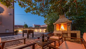Un patio al aire libre con suelo de piedra, mobiliario de madera y una chimenea de piedra.