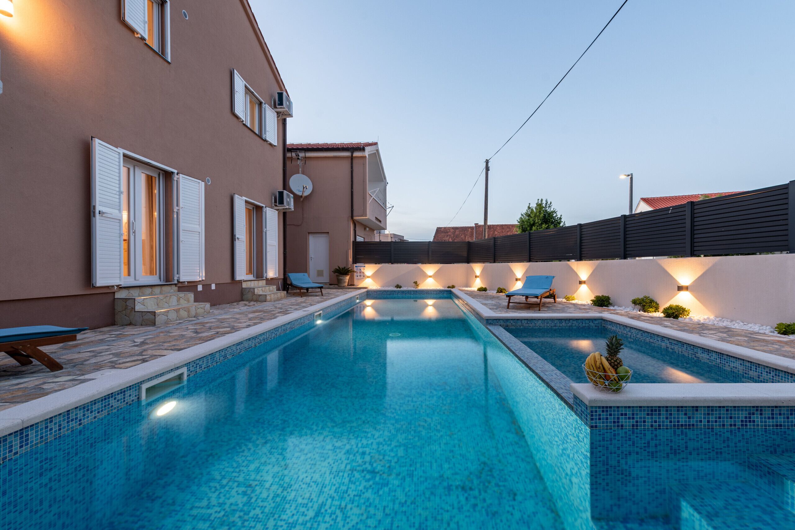 Una piscina con bordes de azulejos, una silla de descanso y una pequeña mesa.