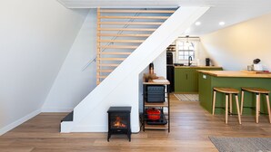 A modern kitchen with a wooden staircase, a built-in stove, and a green island with stools. - 🏠 Mid-Century A-Frame Near Galena | Stargaze | Couples Retreat | 1 Bed/1 Bath (Elizabeth)