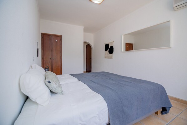 Un dormitorio con cama, armario de madera, espejo y puerta.