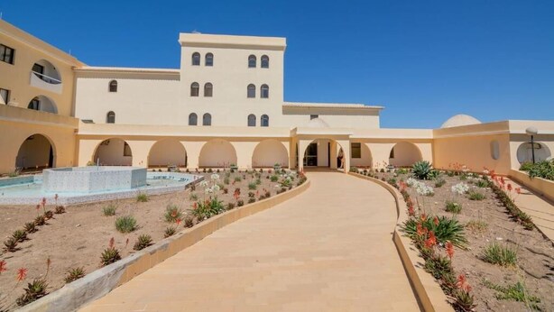 A large building with multiple arches and a central courtyard with a fountain. - Carvoeiro sea view (Carvoeiro)