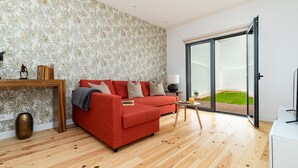 Ein modernes Wohnzimmer mit einem roten Sofa, Holzböden und einer großen Schiebeglas-Tür, die zu einem Garten führt.