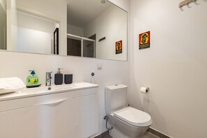 A modern bathroom with a white sink, a toilet, and a large mirror.